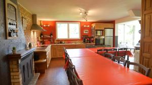 a kitchen with orange walls and a long wooden table at Rêve d'Etretat in Bordeaux-Saint-Clair