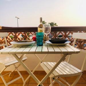 a table with a bottle of wine and glasses on a balcony at Shanti, La Casa Azul in Palm-Mar
