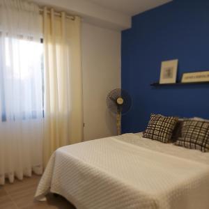 a blue bedroom with a bed and a fan at COCO Guesthouse in Madaba