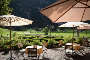 2 Tische und Stühle mit Sonnenschirmen im Garten in der Unterkunft Landgasthof Ruedihus in Kandersteg