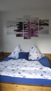 a bedroom with a bed with four paintings on the wall at Ferienwohnung AmmerZonas & AmmerZone in Oberammergau