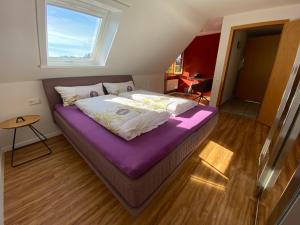 a bedroom with a purple bed with a window at Pia's Nature Retreat in Neukirch