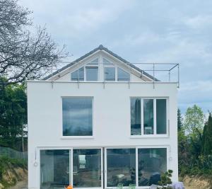 a white house with large windows at Ammersee Haus in Haus,wunderschöne Designerferienwohung mit Garten in Dießen am Ammersee