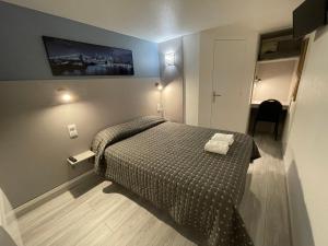 een kleine slaapkamer met een bed met een deken bij Fasthotel Roissy - Saint-Witz in Saint-Witz