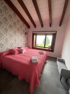 - une chambre avec un grand lit rouge et une fenêtre dans l'établissement Casa Rural Los Abuelos, à Piloña
