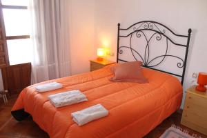 a bedroom with an orange bed with two towels on it at Apartamento Los Laureles in Laroles