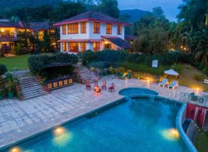 a house with a swimming pool in front of a house at Amritara Ambatty Greens Resort in Virajpet
