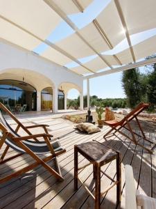 a patio with two chairs and a bench on a deck at Trulli Paradise Ostuni - Villa Privata con Piscina in Ostuni