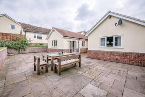 a patio with two benches in front of a house at Grove Farm Bungalow with swimming pool, Dallinghoo in Woodbridge