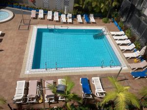 vista sulla piscina con sedie a sdraio e sedie di MARTSARAs PLAYA SARDINA a Sardina