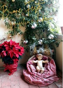 Una bambola seduta su una coperta accanto a un albero di Natale. di Borgo Lucignanello Bandini a San Giovanni dʼAsso