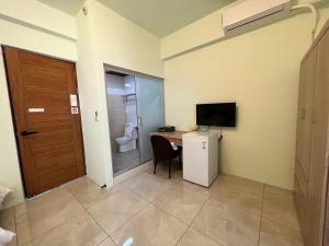 a room with a desk and a toilet and a television at Xingda Port Homestay 