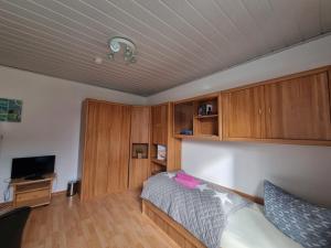 a bedroom with a bed and a tv and wooden cabinets at Mein Urlaub auf Sylt in Westerland