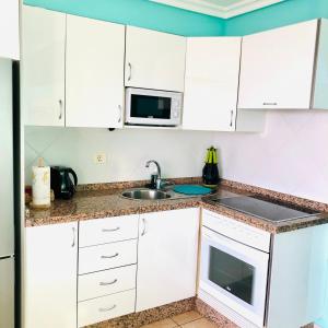 eine Küche mit weißen Schränken, einer Spüle und einer Mikrowelle in der Unterkunft Shanti, La Casa Azul in Palm-mar