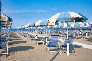 una fila di sedie e ombrelloni in spiaggia di Residence Mediterraneo a Marina di Grosseto