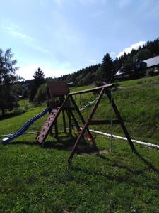 een houten speeltuin met een glijbaan in een veld bij Penzion Alenka in Špindlerův Mlýn