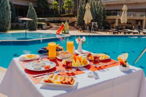 a table with plates of food next to a swimming pool at Ashur Hotel in Dokan
