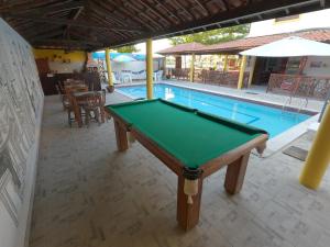 a pool table sitting next to a swimming pool at Pousada Uba-Rio Porto de Galinhas in Porto De Galinhas