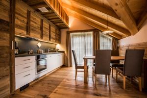 Una cocina y un comedor con mesa y sillas. en Lüch dl Cajer - Appartement Gran crëp, en San Martino in Badia 3 fotos más