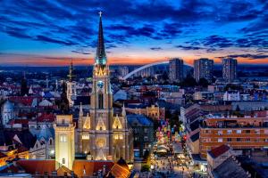 a large building with a steeple in a city at night at Passenger Hostel in Novi Sad