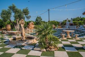 a courtyard with a fountain and a statue on a checkered floor at B&B Giardino Isabella in Palagiano