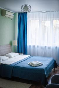 a bedroom with a bed with a blue blanket and a window at Comfort Hotel in Aksay