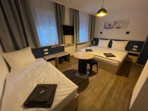 una camera d'albergo con due letti e un tavolo di Hotel Central City Hbf Nürnberg Garni a Norimberga