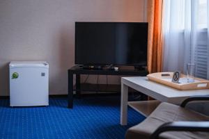 uma sala de estar com uma televisão e uma mesa com uma mesa em Comfort Hotel em Aksay