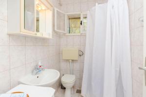 a white bathroom with a toilet and a sink at Apartment Neven in Trogir