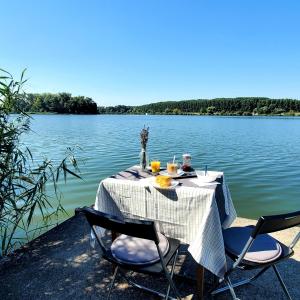 a table with chairs sitting next to a lake at Duna House Duna Ház in Tass