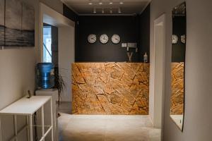a lobby with a stone wall with clocks on the wall at Comfort Hotel in Aksay