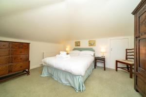 a bedroom with a large white bed and a dresser at Kirkgate Cottage in Eassie and Nevay