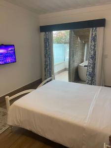 a bedroom with a large white bed and a bathroom at Hotel Boutique Recanto da Passagem in Cabo Frio