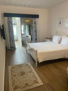 a bedroom with a white bed and a tub and a window at Hotel Boutique Recanto da Passagem in Cabo Frio