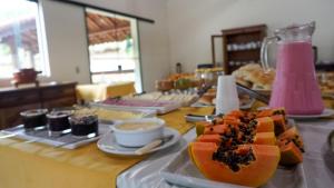 einen Tisch mit Teller mit Lebensmitteln auf einem Tisch in der Unterkunft Pousada Recanto Por do Sol in Morungaba