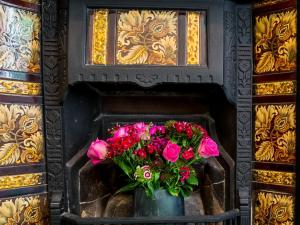 a vase filled with pink flowers in a fireplace at Old Ship Aground in Minehead