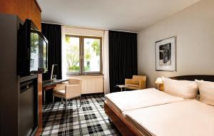 レールテにあるメディアン ホテル ハノーバー レールテのベッドとデスクが備わるホテルルームです。
