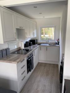 a kitchen with white cabinets and a sink and a window at Chalet 208 In Glan Gwna Caernarfon in Caernarfon