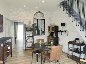 a living room with a table and chairs and a staircase at Duplex contemporain terrasse extérieure parking in Lèves