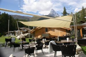 a restaurant with tables and chairs and a mountain at Hotel Hemizeus & Iremia Spa in Zermatt