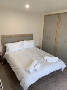 un grande letto bianco con due asciugamani sopra di Whitstable, DP42, 2 bed park home, Alberta Holiday Park a Whitstable Altre 30 foto