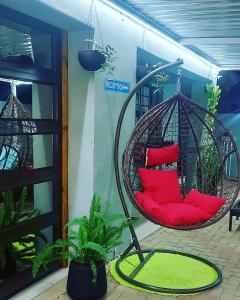a hanging chair with red pillows in a room at Twenty4ten Guesthouse in Gaborone