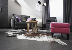 a living room with a couch and a table and a pink chair at Altstadt-Hotel Bielefeld in Bielefeld