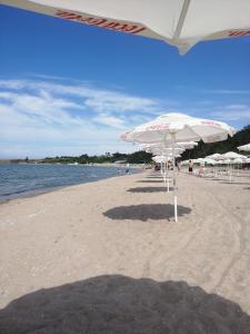 una spiaggia con ombrelloni bianchi e persone sopra di Луксозни вили Св Никола Ахтопол ad Ahtopol