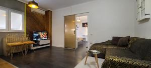 Oro Apartments Tirana في تيرانا: غرفة معيشة مع أريكة وتلفزيون