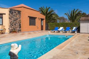 una piscina con sillas azules y una casa en Villa Maravilla piscina climatizada, en Villaverde
