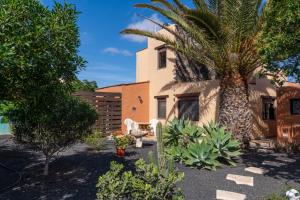 a garden with a palm tree and a building at Villa Maravilla piscina climatizada in Villaverde