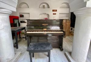an old piano in a room with two tables at Inn Seventh Heaven in Pushkar