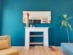 un salon avec un miroir sur un mur bleu dans l'établissement Appartement MARLENE - Lumineux - Terrasse - WIFI - Clim - Ajaccio, à Ajaccio