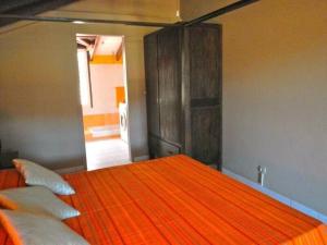 una camera da letto con letto completo di lenzuola e cuscini arancioni di duplex, 2 bedrooms, 2 couples sea view overlooking the village of DESHAIES a Deshaies